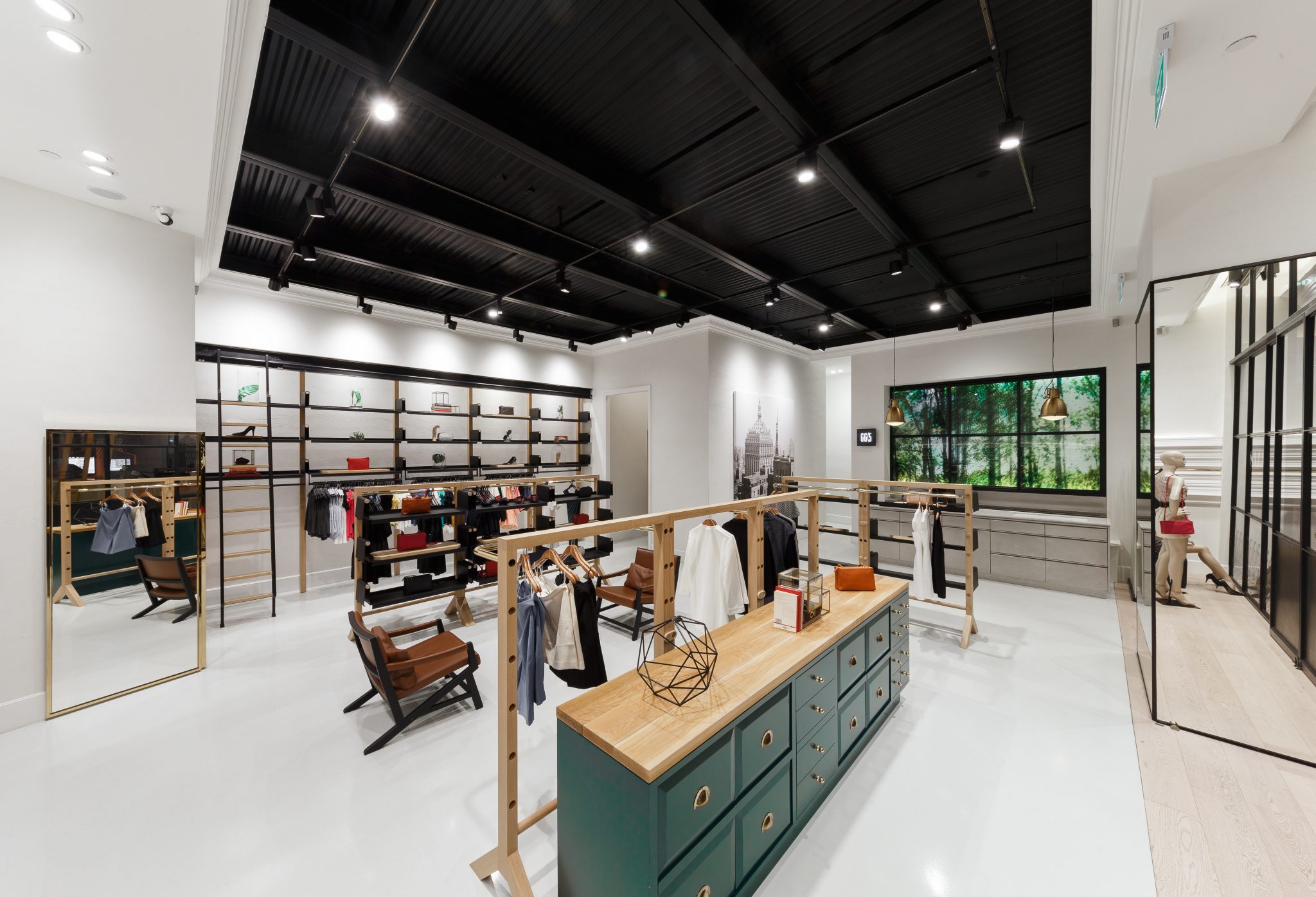 GG<5 retail flagship by PIU: black industrial ceiling over pale timber fixtures and a green island counter