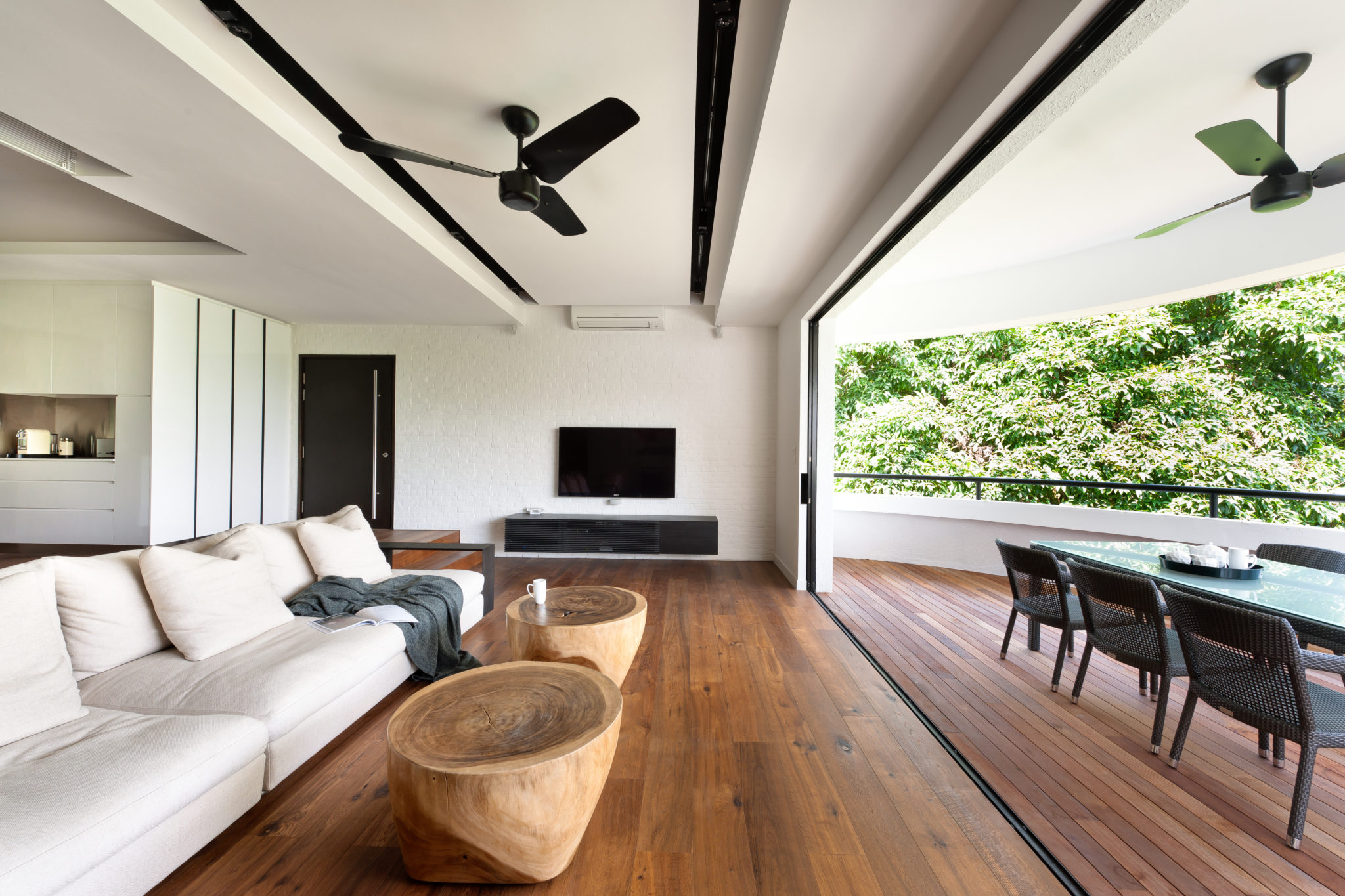 Regency Park by PIU: white living room with black ceiling fans and timber floor opening onto a green veranda
